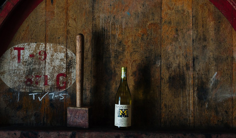 Bottle of Mayacamas Chardonnay in front of large wooden barrel