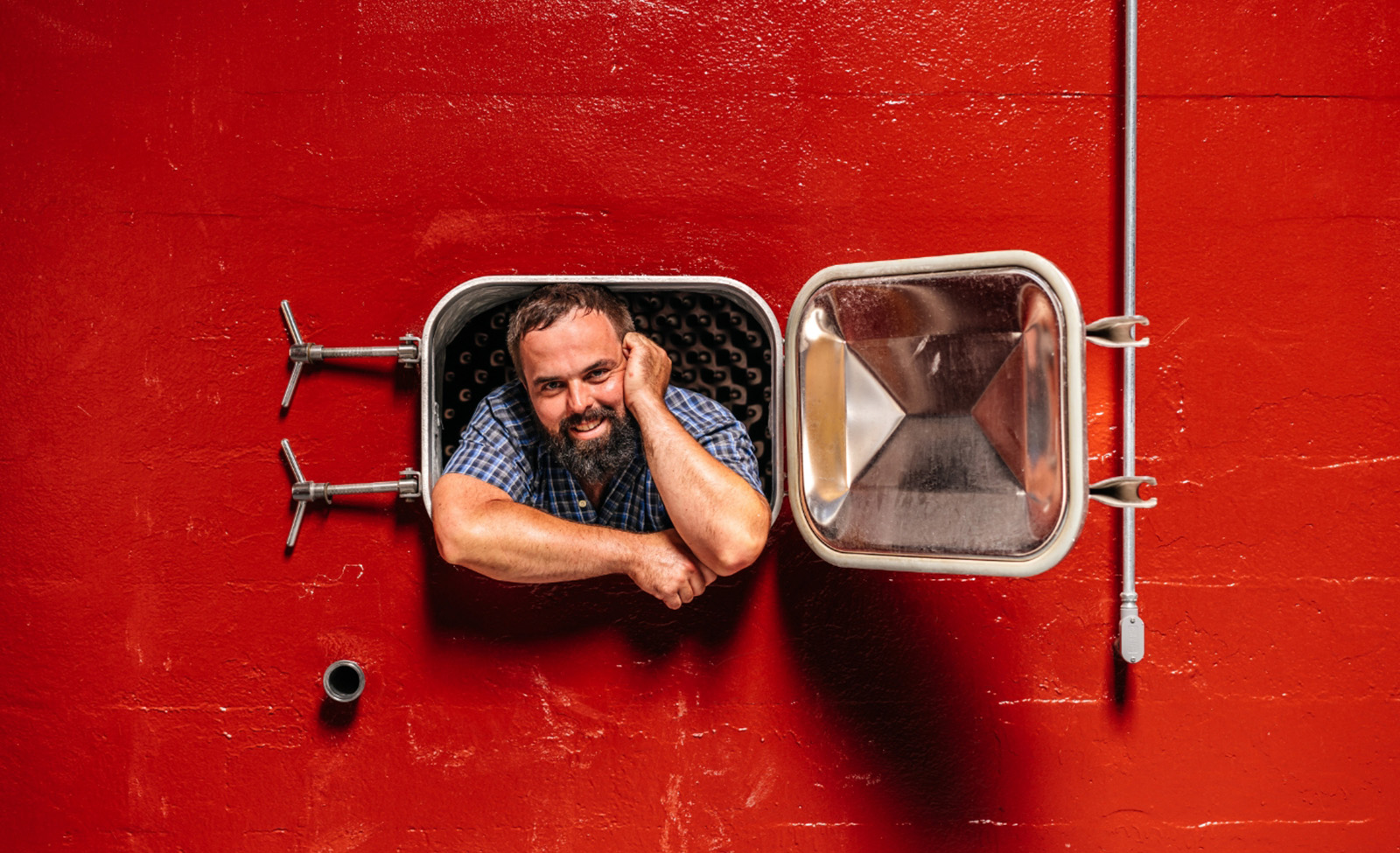 Mayacamas winemaker peaking out from door or red fermentation tank